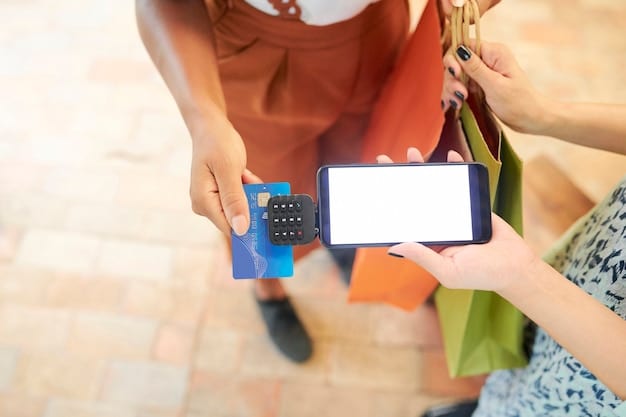 A person's hand holding a credit card over a smartphone screen displaying a cashback app with various shopping categories and percentages. The background is a blurred shopping mall environment.