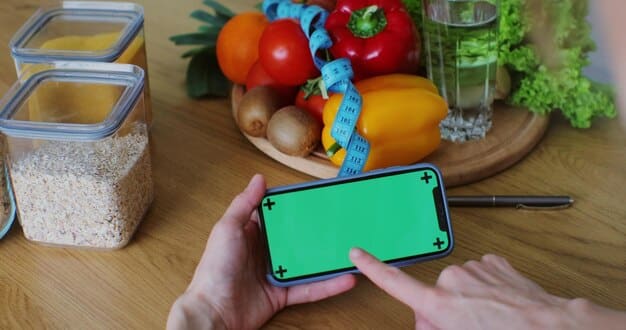A smartphone displaying a cashback app interface, with various grocery store logos and cashback percentages, surrounded by fresh fruits and vegetables on a kitchen counter.