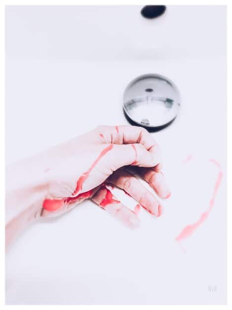 A close-up of a hand holding a magnifying glass over a computer screen, focusing on text reviews with some highlighted as suspicious, implying review analysis and detection.